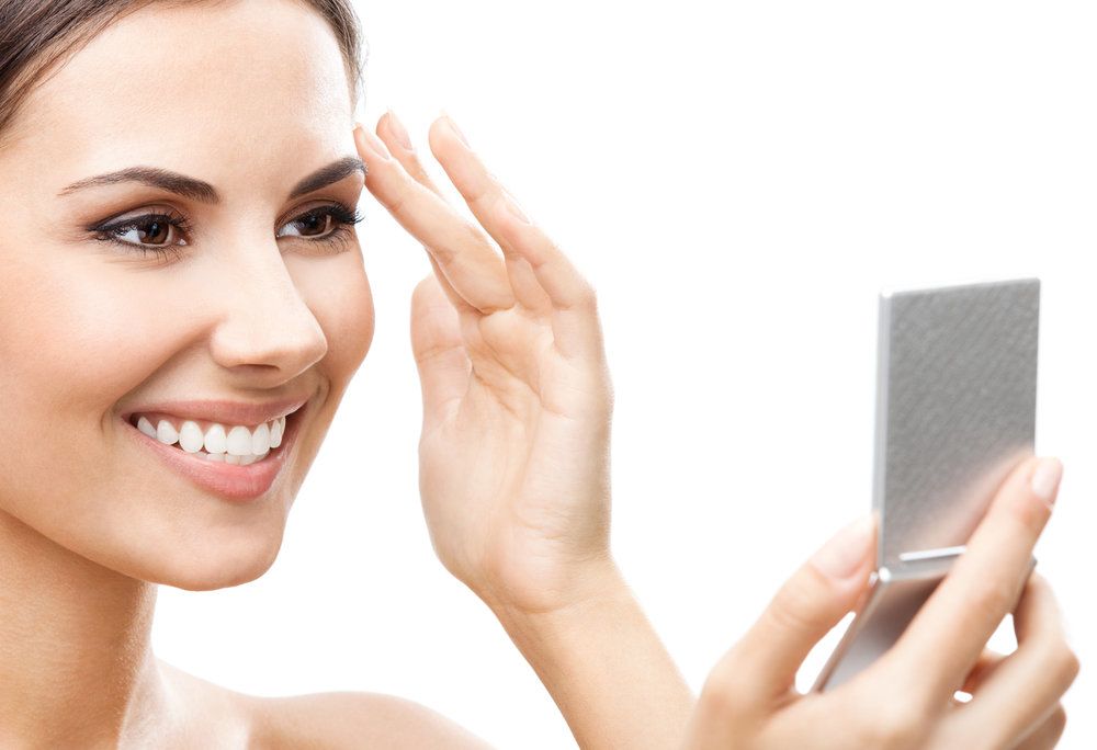 Attractive woman admiring appearance in compact mirror