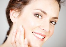 Woman with smooth, youthful skin smiling and holding hand to cheek